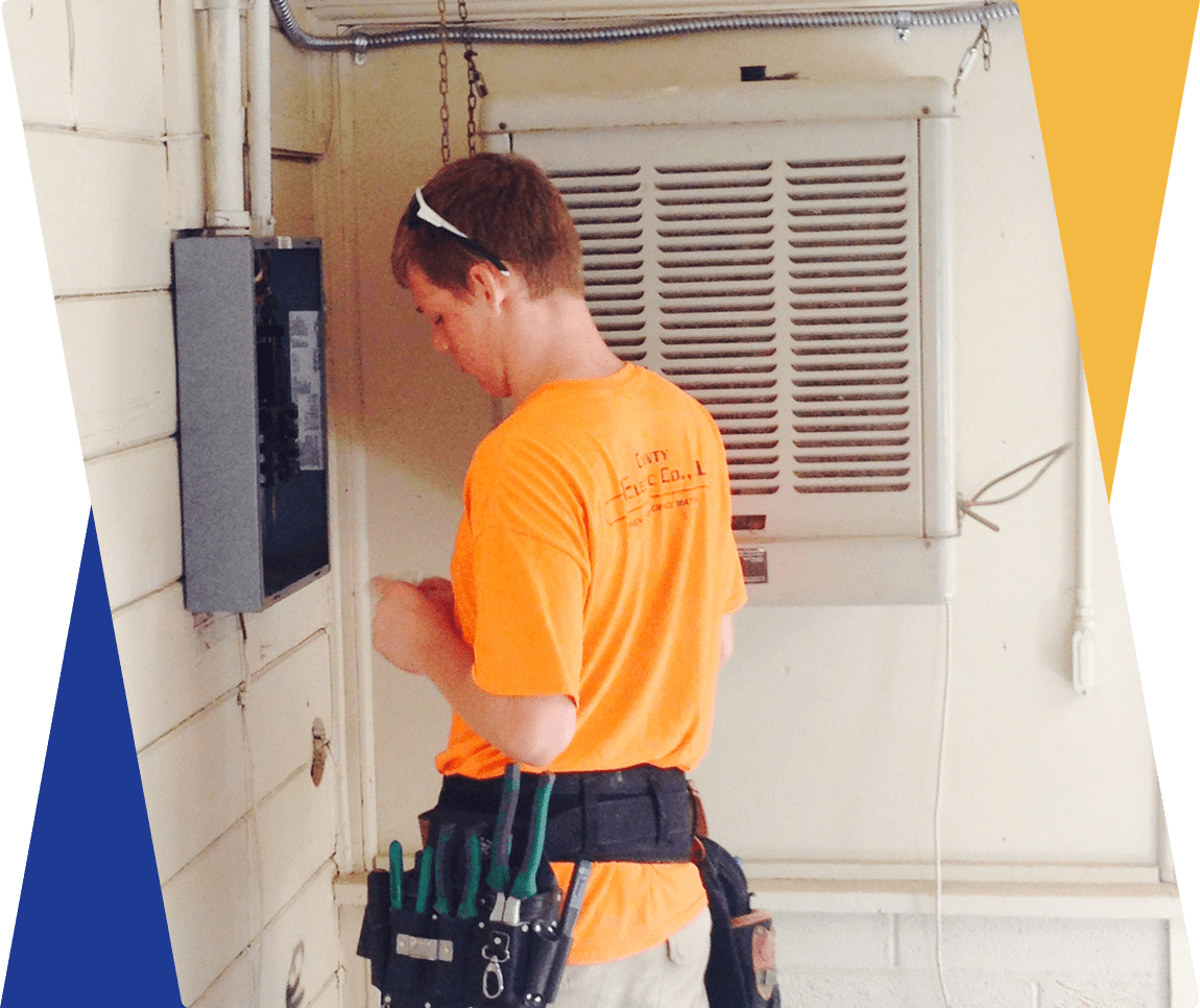Electrician working on wall-mounted electrical panel.