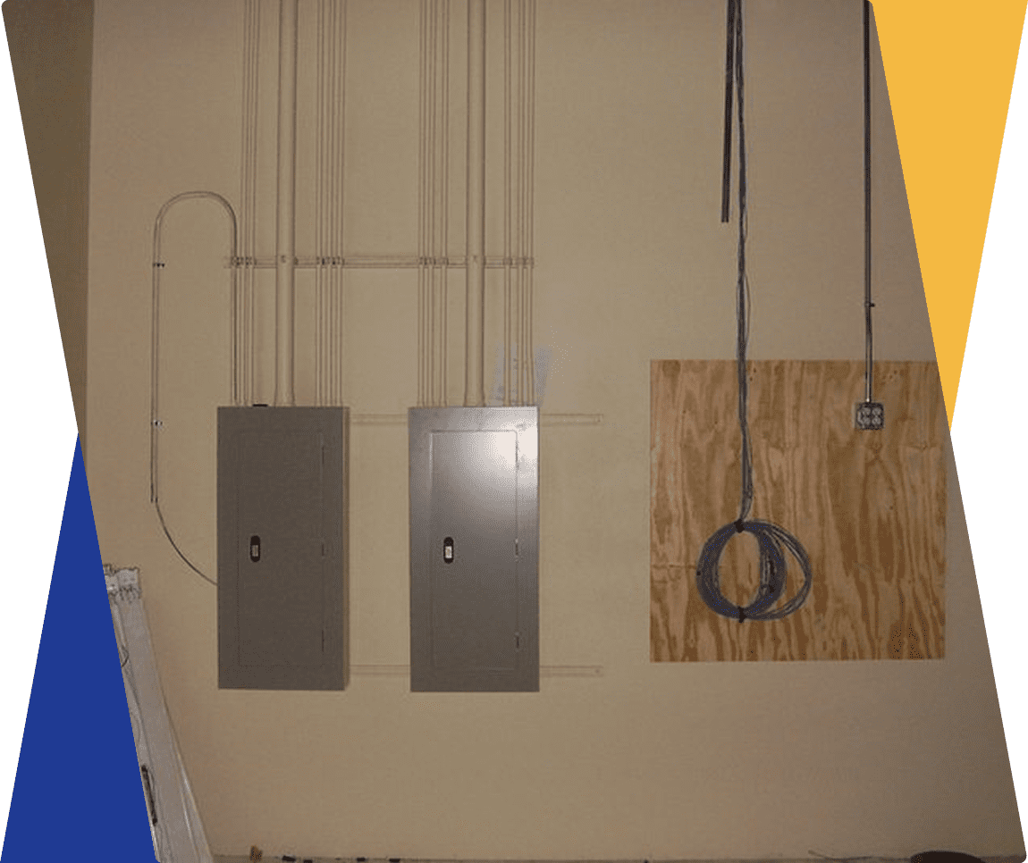 Electrical panels and cables on unfinished wall.
