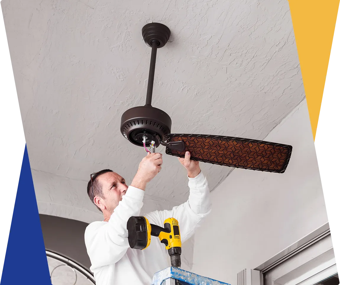 Man installing a ceiling fan indoors.
